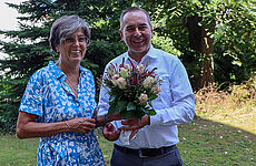 Ein Mann überreicht einer Frau Blumen und einen Geschenkgutschein.