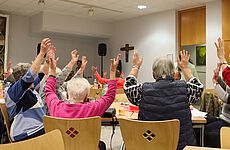 Sitzende Menschen halten ihre Hände nach oben.