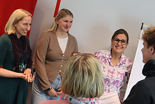 Fünf Personen stehen im Kreis zusammen.