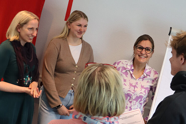 Fünf Personen stehen im Kreis zusammen.