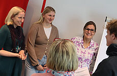 Fünf Personen stehen im Kreis zusammen.