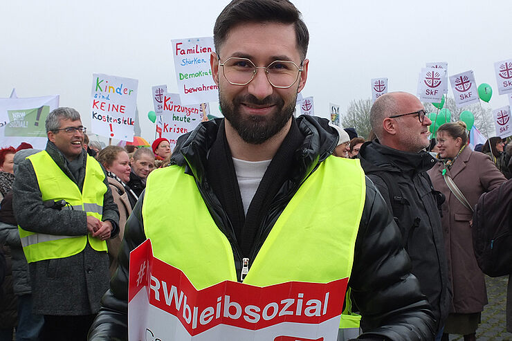 Ein Mann in Warnweste steht vor einer Gruppe Menschen.