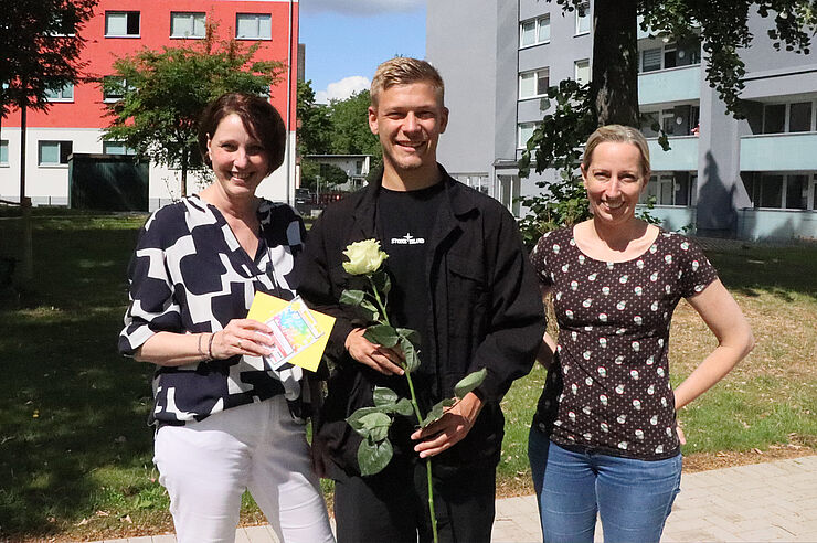 Drei Personen stehen zusammen.