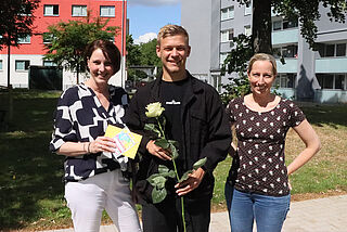 Drei Personen stehen zusammen.