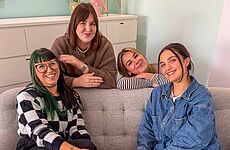 Vier junge Frauen lächeln in die Kamera.