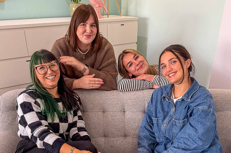 Vier junge Frauen lächeln in die Kamera.