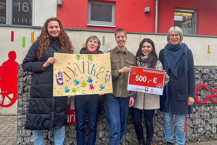Fünf Frauen stehen zusammen und halten ein buntes Bild mit Aufschrift "Danke" und einen Scheck in den Händen.