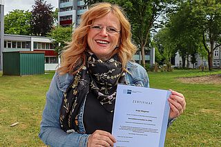 Eine Frau zeigt ein Zeugnis.