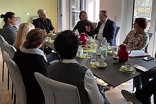 Mehrere Personen sitzen um einen Tisch herum.