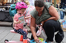 Ein kleines Kind und seine Mutter durchstöbern einen Korb mit Büchern.