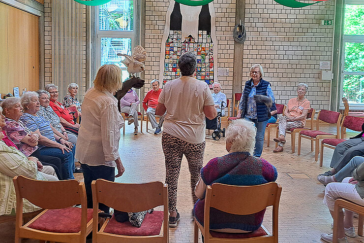 Eine Frau steht in einer Runde Menschen, eine Schleiereule sitzt auf ihrem Arm.