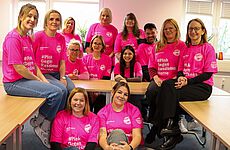 Eine Gruppe Menschen in pinkfarbenen T-Shirts steht zusammen.