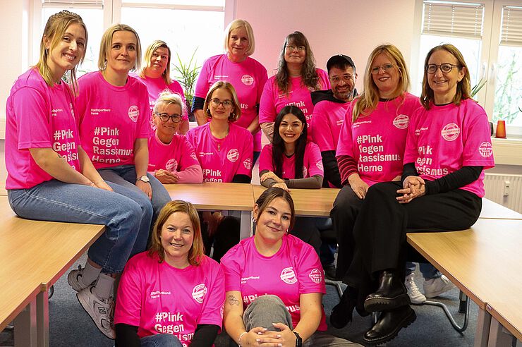 Eine Gruppe Menschen in pinkfarbenen T-Shirts steht zusammen.