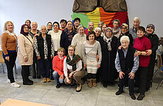 25 Frauen stehen zusammen und lächeln in die Kamera.