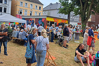 Viele Menschen stehen auf einer Wiese.