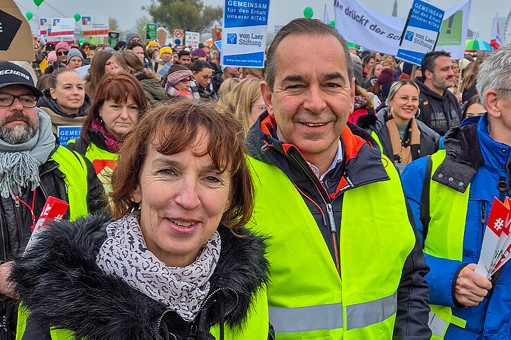 Eine Frau und ein Mann stehen vor mehreren Menschen.