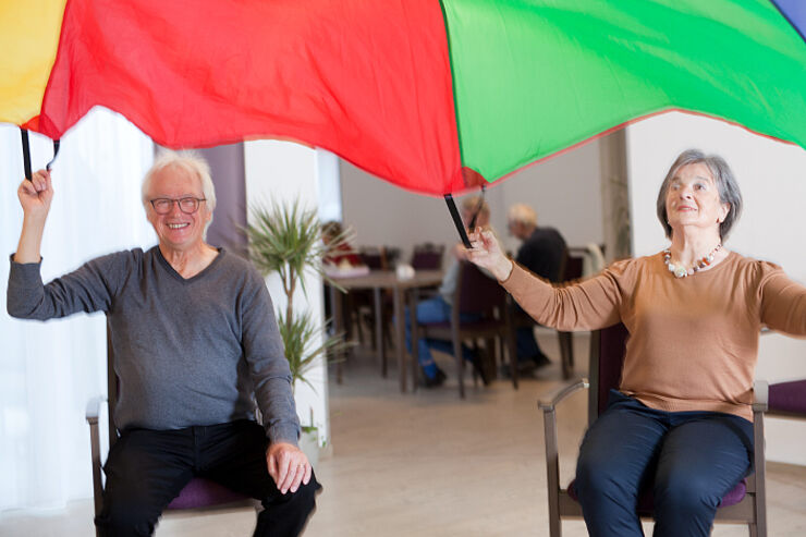 Ein Mann und eine Frau halten ein buntes Tuch hoch