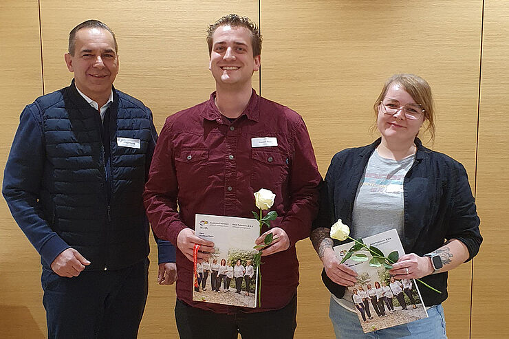 Zwei Männer und eine Frau stehen nebeneinander.
