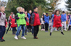 Mehrere Kinder in bunten Trikots springen in die Luft.