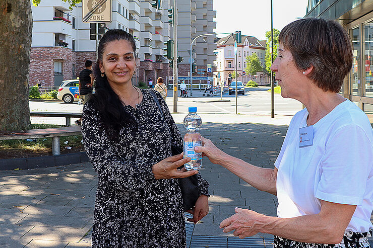 Eine Frau gibt einer anderen Frau eine Wasserflasche.