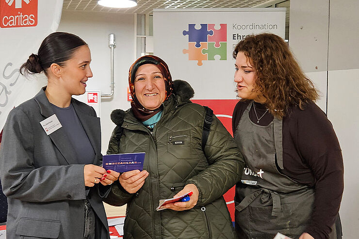 Drei Frauen stehen zusammen und sprechen miteinander.