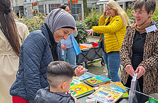 Mutter und Kind stehen am Caritas-Bücherstand