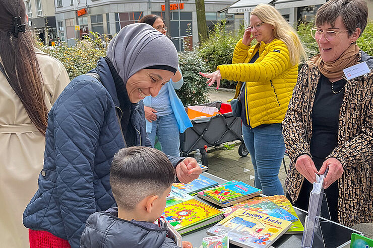 Mutter und Kind stehen am Caritas-Bücherstand