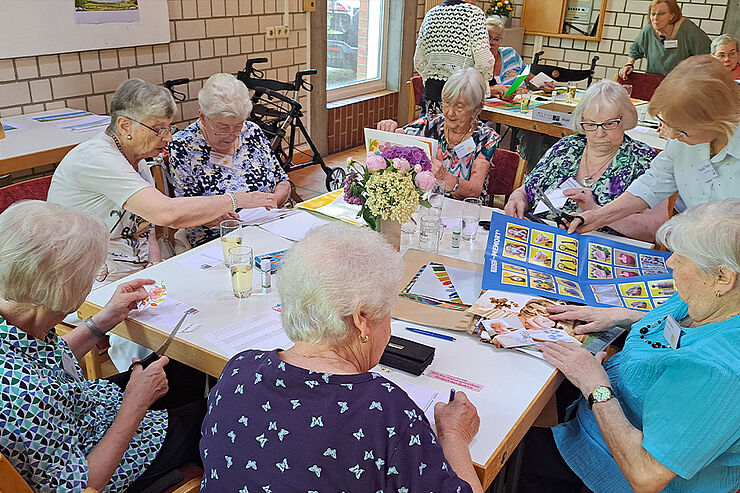 Mehrere Frauen sitzen am Tisch und basteln.