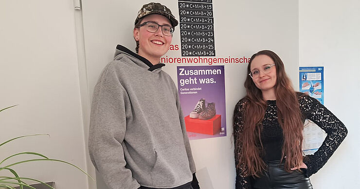 Zwei junge Menschen stehen vor einem Plakat mit der Aufschrift Zusammen geht was.